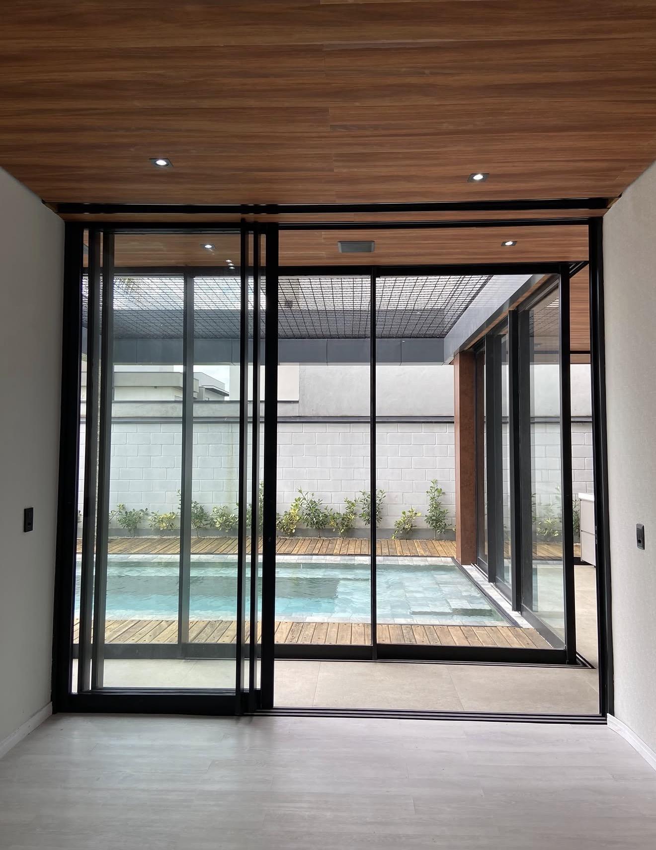 Ambiente com esquadrias piso ao teto e vista para a piscina